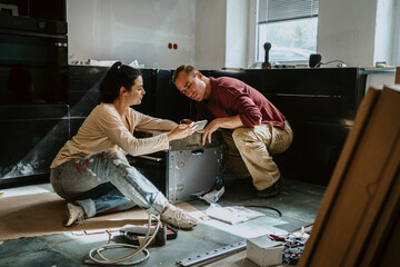 Couple discussing over mobile phone while renovating kitchen at home
