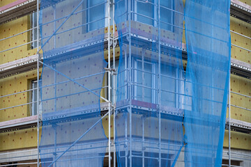 Fiberglass insulation cold barrier in facade on Construction site. Modern Building technologies and construction materials. New apartment building in Europe. Scaffolding around the wall.