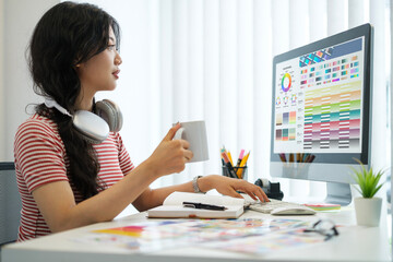 Side view of young woman sitting at graphic studio and choosing color for creative project on...