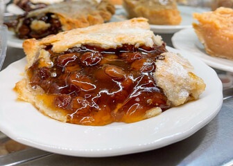 A slice of raisin pie with a sugar dusted double crust on a white plate