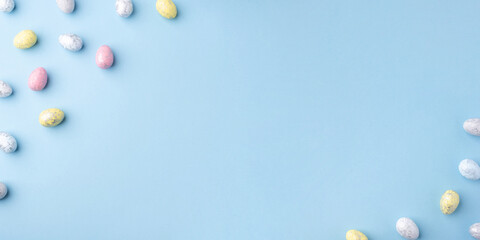 Festive Easter background. Multicoloured Easter eggs on a blue table. Card with a place for text. Top view.