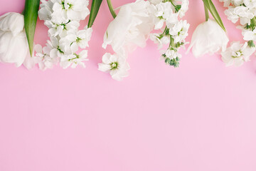 Obraz na płótnie Canvas Happy Mothers day and Womens day. Stylish white flowers flat lay on pink background, space for text. Beautiful tender tulips and spring flowers border, greeting card template. Floral banner