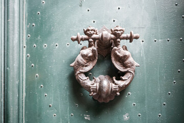 Close up of a metal door knocker on a green wooden door
