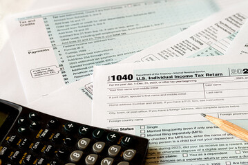 IRS 1040 tax form with calculator and pencil on a table. Tax time USA. - obrazy, fototapety, plakaty