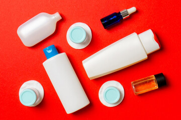 Set of travel size cosmetic bottles on colored background. Flat lay of cream jars. Top view of bodycare style concept