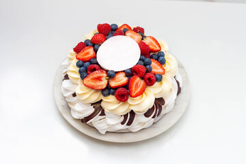 Pavlova cake with whipped cream cheese, chocolate sauce and fresh berries on marble grey background