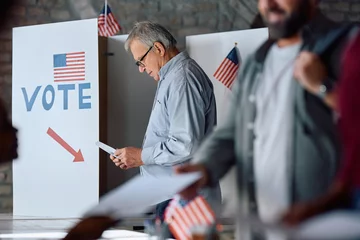 Deurstickers Senior US citizen at voting booth at polling station. © Drazen