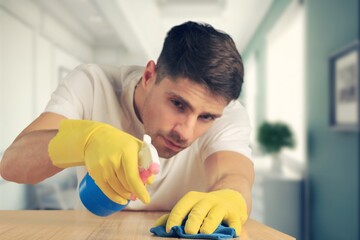 Person cleaning using cloth and disinfectant in room
