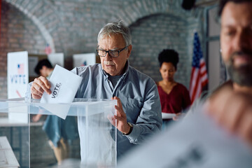 Senior American citizen voting at polling place. - obrazy, fototapety, plakaty