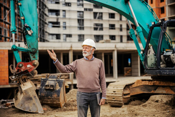 An elder construction manager is visiting construction site.