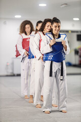 Taekwondo girls in row standing in doboks and preparing for martial art class.