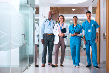 Portrait Of Smiling Multi Cultural Medical Team Wearing Scrubs And White Coats In Modern Hospital  - obrazy, fototapety, plakaty