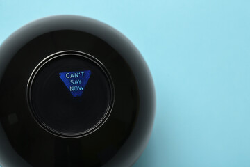 Magic eight ball with prediction Can't Say Now on light blue background, top view. Space for text
