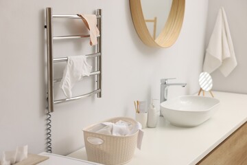 Heated towel rail with underwear on white wall in bathroom