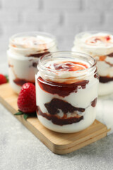 Tasty yoghurt with jam and strawberry on grey table, closeup