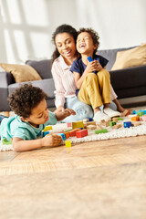 focus on cute african american boy playing while his blurred mother and brother smiling on backdrop