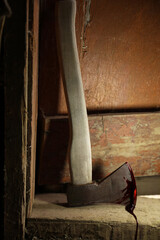Axe with blood on wooden threshold indoors