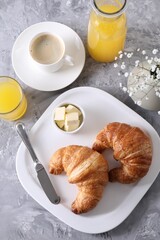 Tasty breakfast. Fresh croissants, coffee, juice and butter on grey table, flat lay