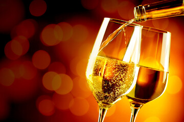 Pouring white wine into glass against dark background with blurred lights, closeup. Space for text