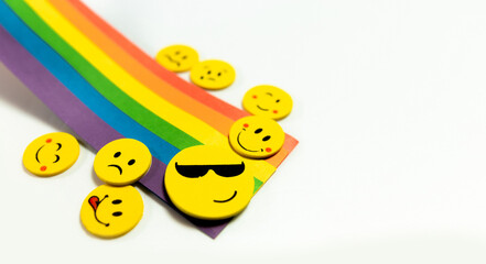 A row of smiling faces with one of them wearing sunglasses. The faces are arranged in a rainbow pattern..