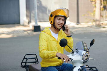 Smiling motorbike taxi driver calling passenger