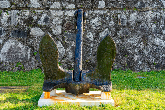 Anchor of a ship painted black on display next to the walls of the S&atilde;o Braz fort