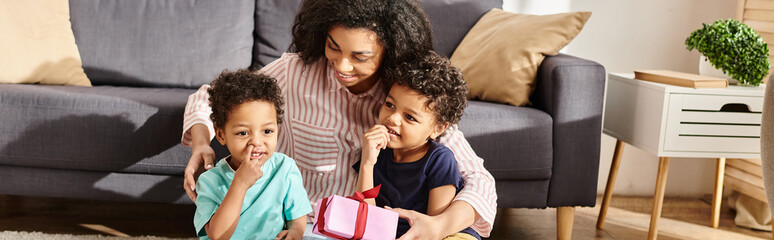 merry beautiful african american woman posing with her little two sons with present, Mothers day