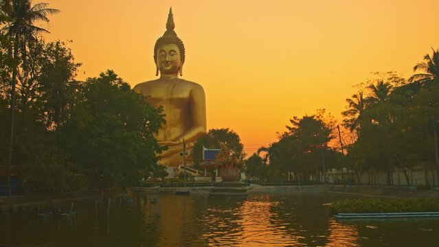 scenery yellow sky at sunset behind the biggest buddha..reflection of yellow sky in the pool. .golden big buddha popular landmark at wat Muang Ang Thong Thailand..