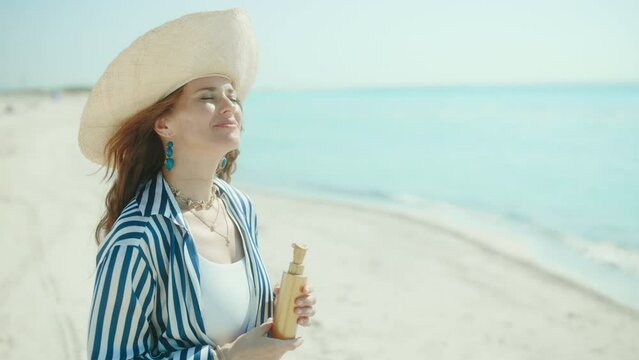 smiling elegant female on the seacoast with sunscreen.