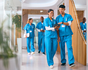 Multi Cultural Medical Team Wearing Scrubs Walking Along Corridor In Modern Hospital 