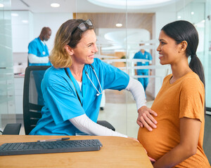 Female Nurse Or Doctor Wearing Scrubs Examining Pregnant Woman In Hospital Obstetrics Clinic