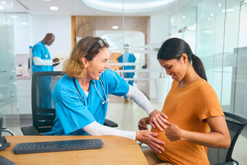Female Nurse Or Doctor Wearing Scrubs Examining Pregnant Woman In Hospital Obstetrics Clinic