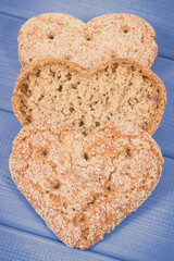 Fresh wholegrain bread in shape of heart for breakfast. Purple boards