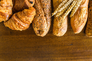 Frame of various french breads (baguette, croissants, chocolate pies) and bunch of wheat's ears on...