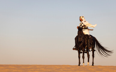 Saudi man in a desert with his  black stallion