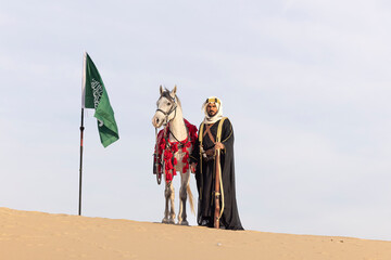 Saudi man with his horse in a desert, with hunting riffle