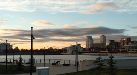 View from the embankment to the river and buildings in the city in the evening at sunset