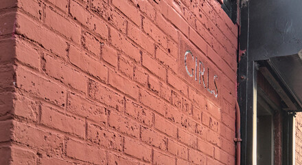 Fototapeta na wymiar girls sign on red brick wall of ladies room in old building inside public park (restroom, bathroom, rest room, wash room, water closet, women's wc entrance)