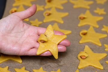 Funny raw Star cookies with nut in palm of pastry chef on background of baking sheet with cookies