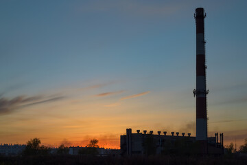 Fototapeta na wymiar Boiler room with a tall chimney at dusk the backdrop of a picturesque sky at sunset