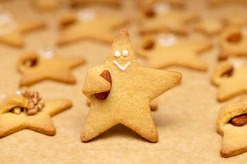 Funny Star cookie with a nut in hand and a face close-up on the background of baked cookies