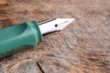 Green fountain pen wooden background.