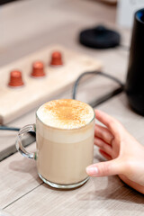 a hand taking a cup of cappuccino in the coffee shop