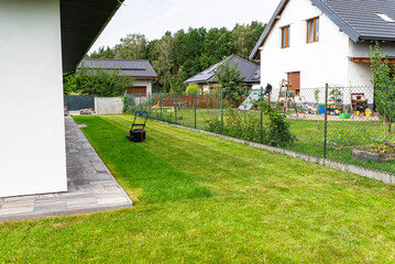 Mowing grass with an electric, powered mower, with a cutting width of 44 cm, visible mown rows.