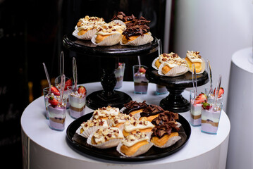 Eclairs on candy bar for wedding banquet, birthday party, baptism. Pastries with cream and chocolate on a black plate.