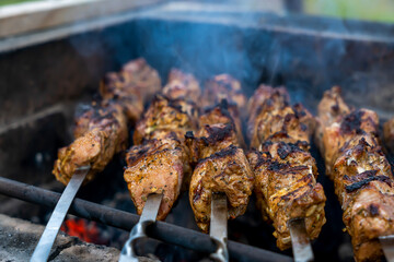 Barbecue on the grill. Grilled kebab cooking on metal skewer, close up