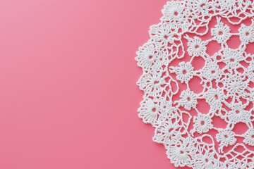 White crochet napkin against a pink background with copy space.