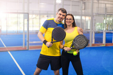 Family team mx. Group of two mix padel tennis players with racket. Woman and man athletes with paddle racket on the blue court. Sport concept. Download a high quality photo for a sports app. - 750815556