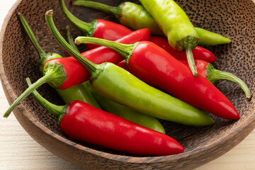 Bowl with whole fresh raw green and red hot rawit peppers close up