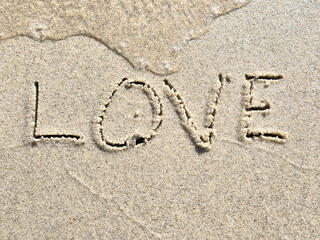 Love text in beach sand with water edge outline